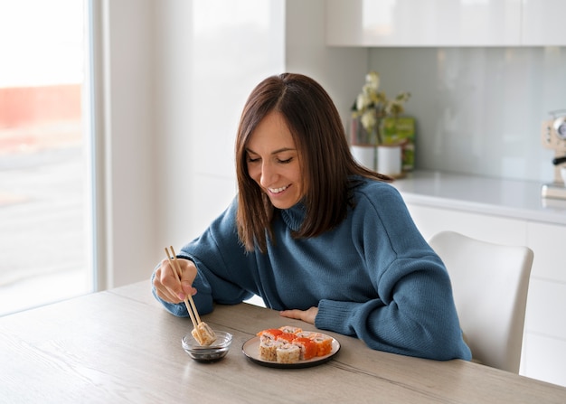 Medium shot woman eating sushi at home