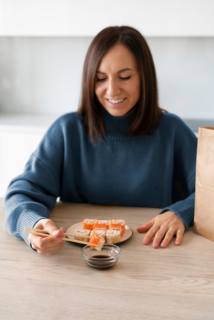 Женщина среднего роста ест суши дома