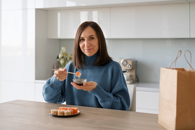 Medium shot woman eating sushi at home