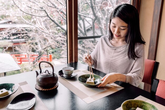 箸で食べるミディアムショットの女性