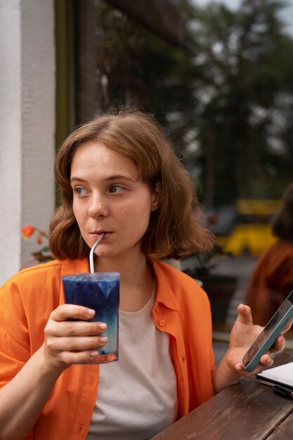 Medium shot woman enjoying a blue matcha