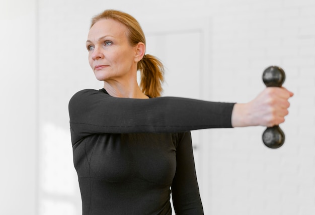 Medium shot woman exercising with dumbbell