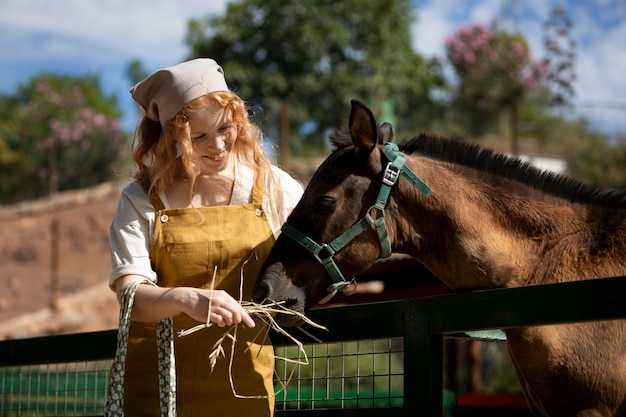 Medium shot woman feeding horse