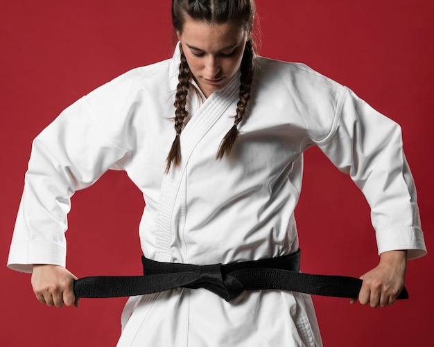 Medium shot of woman fighter straighten her belt