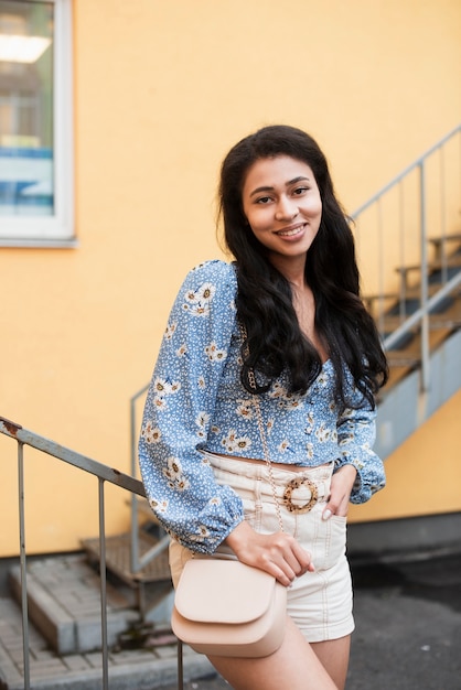 Free photo medium shot of woman in front of stairs looking at camera