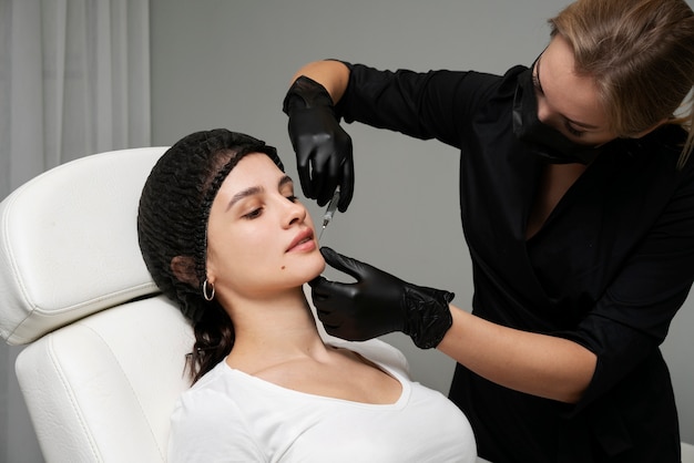 Free photo medium shot woman getting lip fillers at clinic