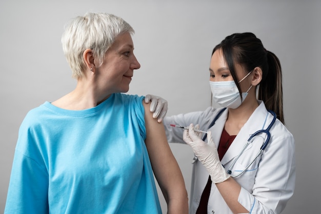 Foto gratuita donna di tiro medio che viene vaccinata