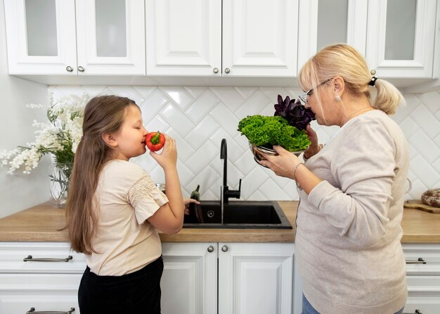Женщина и девушка среднего размера, нюхающие овощи