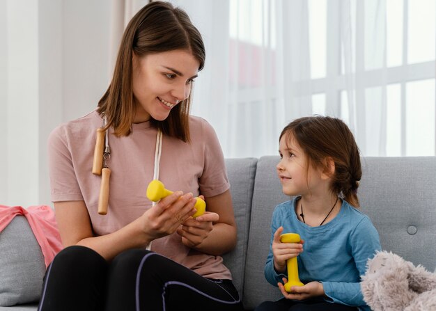 ミディアムショットの女性とダンベルの女の子