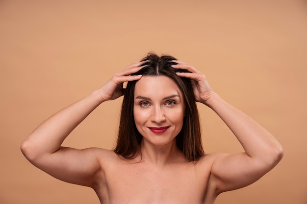 Женщина среднего роста, делающая себе массаж головы.