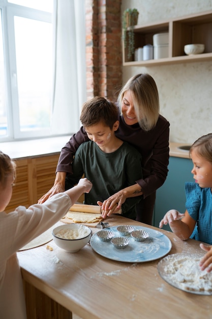 Donna del colpo medio che aiuta i bambini a cucinare