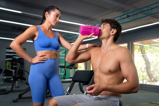 Medium shot woman helping man at gym