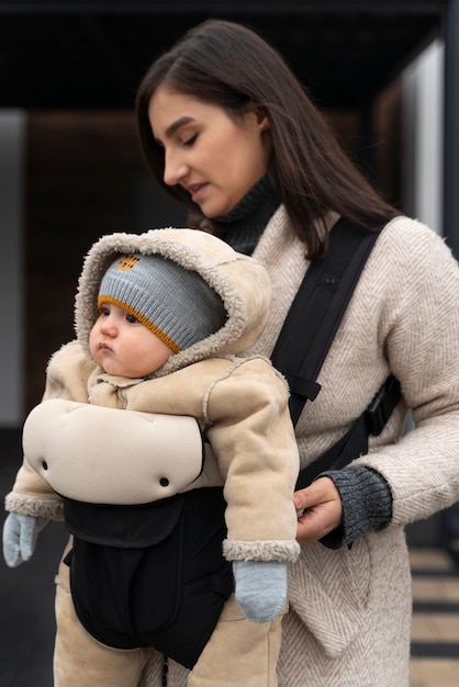 Donna del colpo medio che tiene bambino in marsupio