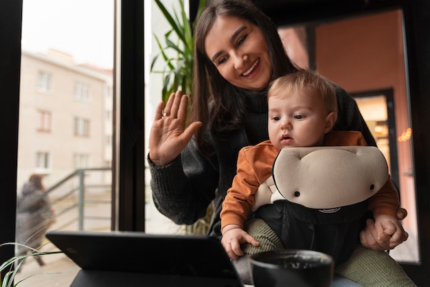 Free photo medium shot woman holding baby in carrier