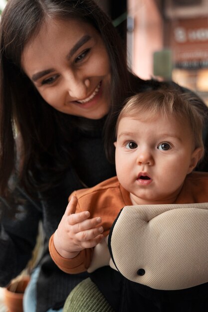 medium shot woman holding baby in carrier