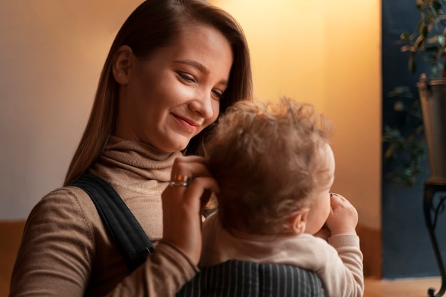 Free photo medium shot woman holding baby in carrier