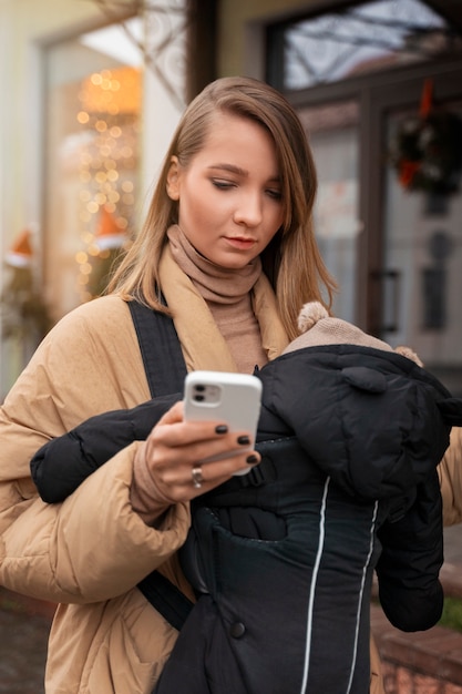 Free photo medium shot woman holding baby in carrier