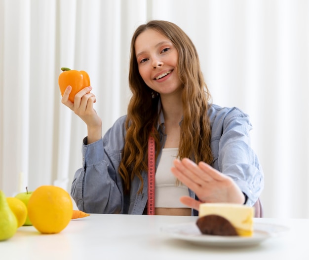 Medium shot woman holding bell pepper