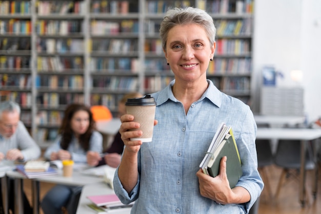 Medium shot woman holding books and cup