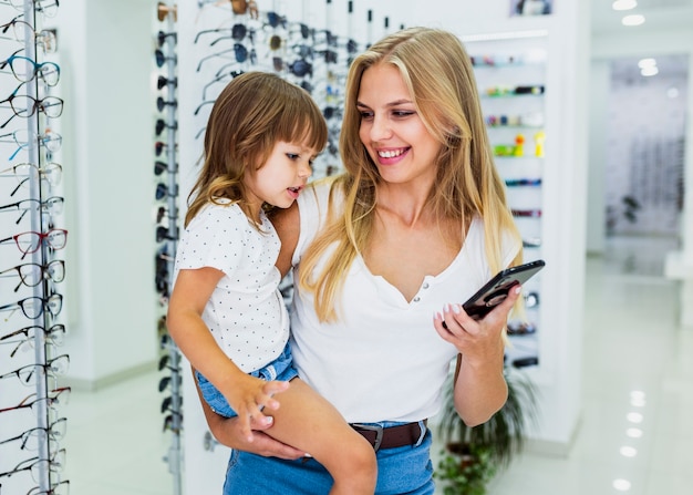 子供と電話を保持している女性のミディアムショット