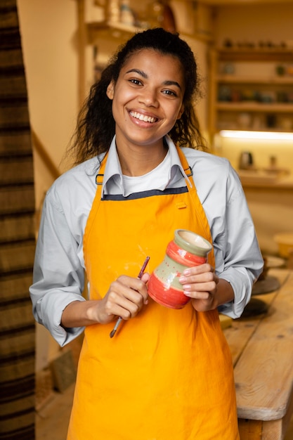 Medium shot woman holding clay pot