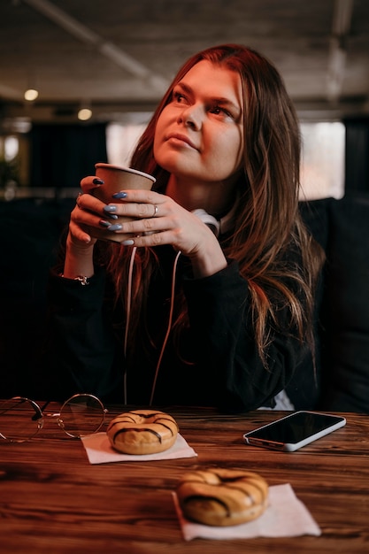 コーヒーカップを保持しているミディアムショットの女性