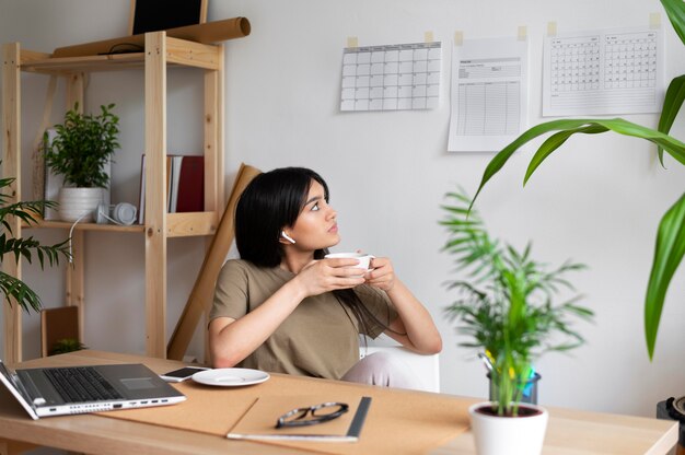 コーヒーカップを保持しているミディアムショットの女性