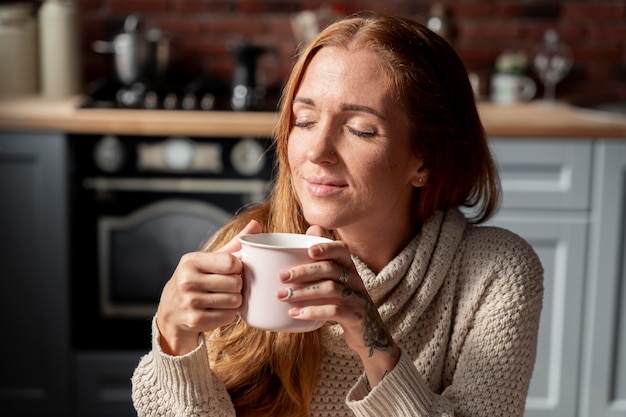 コーヒーカップを保持しているミディアムショットの女性