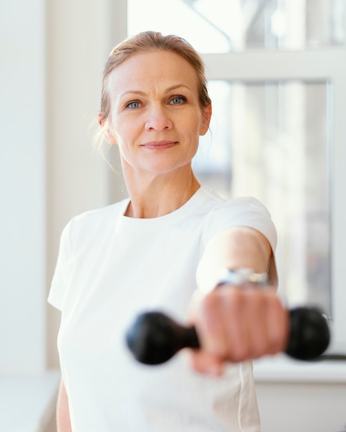 Medium shot woman holding dumbbell