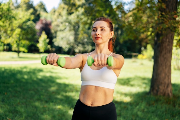 Medium shot woman holding dumbbells