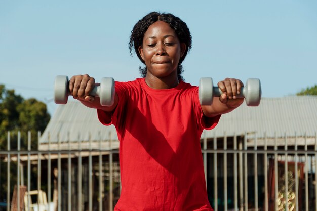 Medium shot woman holding dumbbells