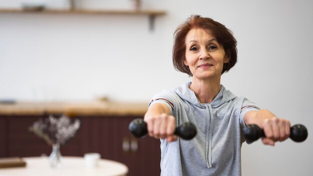 Medium shot woman holding dumbbells