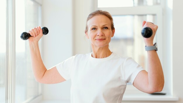 Medium shot woman holding dumbbells