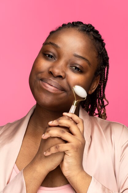 Medium shot woman holding face roller