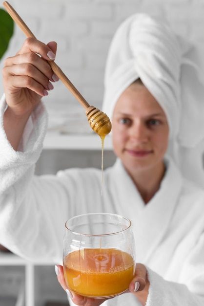 Medium shot woman holding honey jar