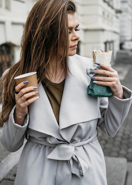 Medium shot woman holding kebab and coffee