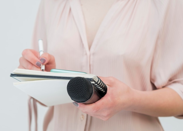 Medium shot woman holding microphone and writing notes