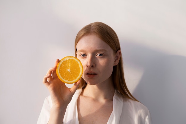 Женщина среднего роста держит дольку апельсина