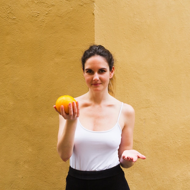 Medium shot woman holding an orange