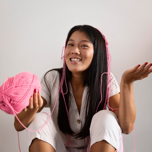 Foto gratuita donna del colpo medio che tiene filo rosa