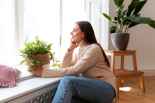 Free photo medium shot woman holding plant pot