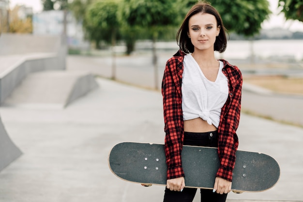 Medium shot of woman holding skateboard