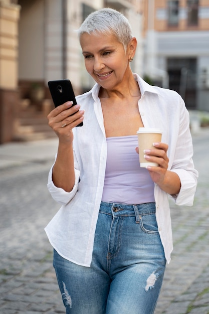 Foto gratuita donna con colpo medio che tiene smartphone