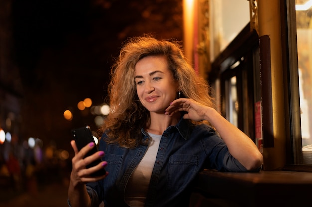 Medium shot woman holding smartphone