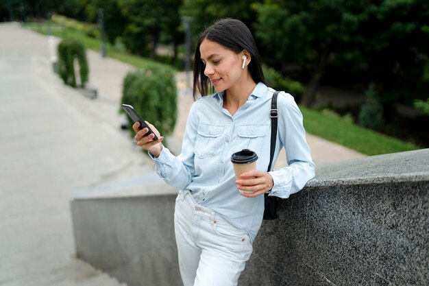 Medium shot woman holding smartphone