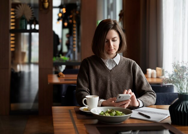 Medium shot woman holding smartphone