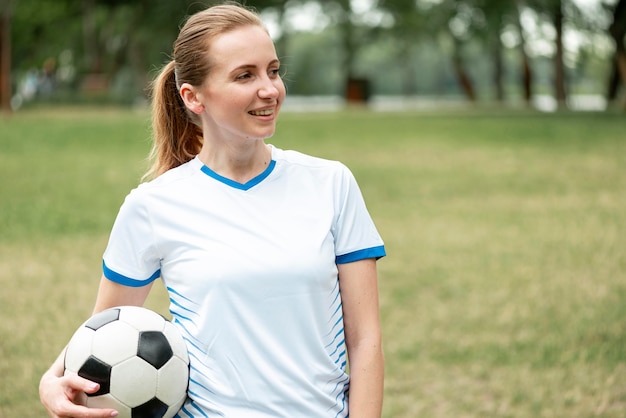 Medium shot woman holding soccer ball