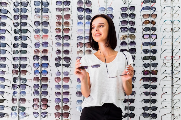 Medium shot of woman holding sunglasses pairs