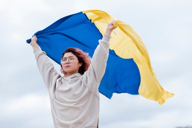 ウクライナの旗を保持しているミディアムショットの女性