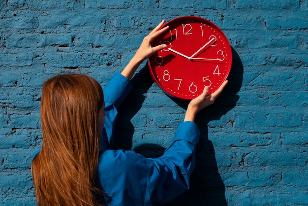 Foto gratuita donna del colpo medio che tiene l'orologio da parete